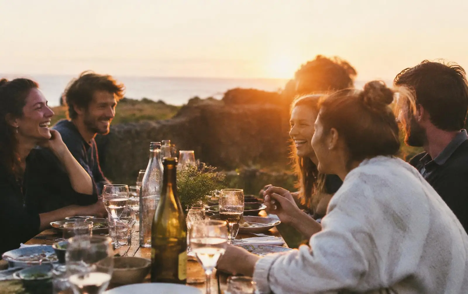Amis partageant un repas en extérieur au coucher du soleil, univers Vivre EXPERIENTIEL